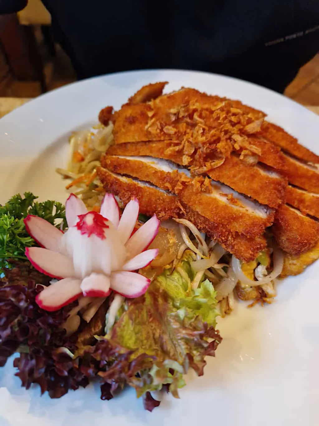 Paniertes Hühnerfleisch mit Salat und Blütendekoration